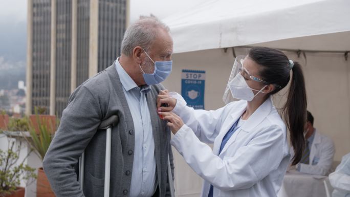 拉丁美洲卫生保健工作者在一名老年患者接种2019冠状病毒疾病疫苗后贴上标签