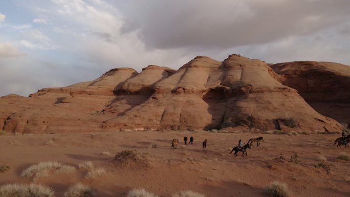 纳瓦霍族在亚利桑那州纪念碑谷的土地上骑马，背景是标志性的纪念碑