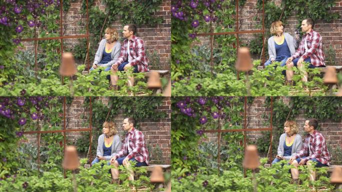 一对从园艺中休息的夫妇在后院的长凳上聊天
