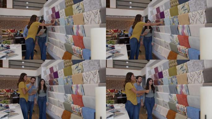 在一家面料店，一位年轻开朗的女售货员一边帮一对夫妇挑选面料，一边在平板电脑上向他们展示设计