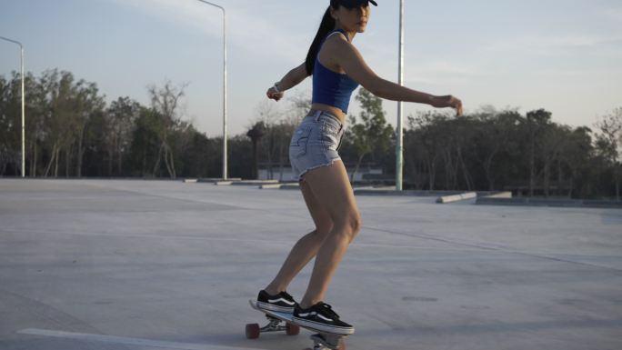 在美丽的夏日，亚洲女性在户外冲浪、滑冰或滑板。早上，快乐的年轻女性在公园玩冲浪溜冰。