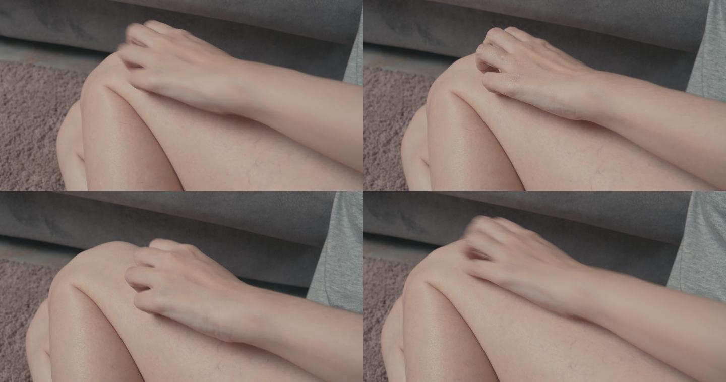 4k分辨率的亚洲美女坐在家里的沙发上，用手抓着发痒的皮肤腿。虫咬痛的。医疗保健概念。