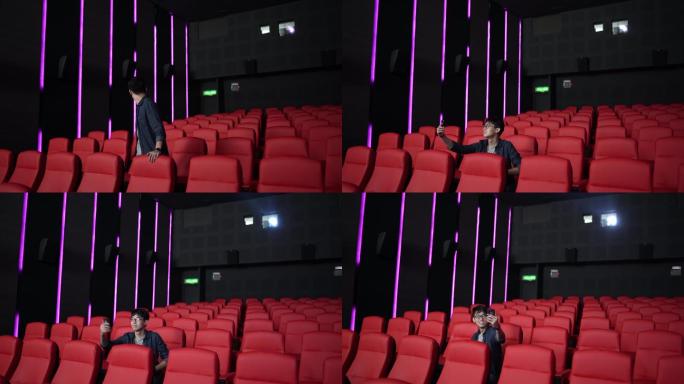 中国亚裔年轻人独自在电影院看电影时用手机自拍