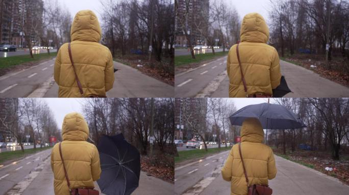 雨天走路时，穿着黄色夹克的女人打着伞