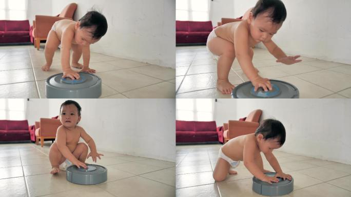 亚洲小男婴在家玩机器人吸尘器。现代科技、儿童、学习、婴儿的第一步