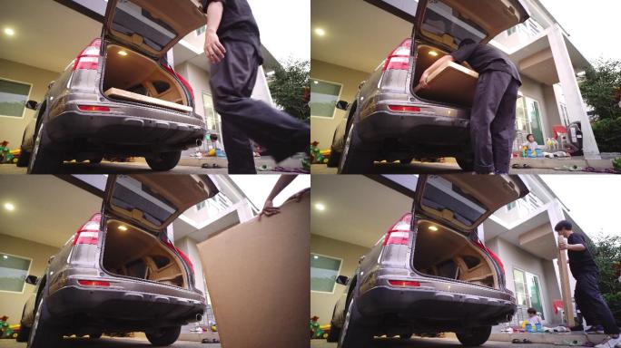 一名亚裔男子将一个纸板箱从汽车行李箱搬进新居