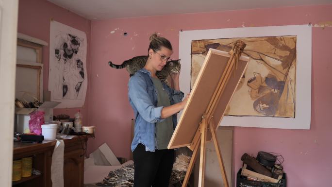 在家画或画图画的肩上扛着猫的年轻女子