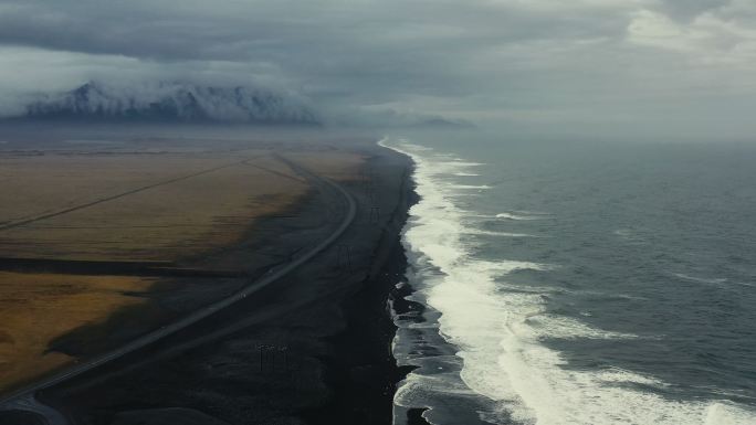 鸟瞰冰岛引人注目的黑色沙滩，沙滩上有冰山和山脉