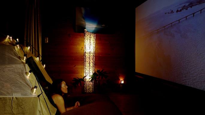 一个女人在家里露营，在大投影屏幕上看电影
