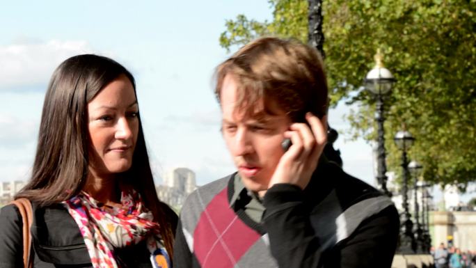 伦敦泰晤士河堤岸的一对夫妇，电话中的男人