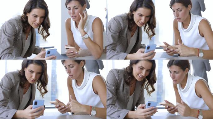 商界女性坐在智能手机旁，兴高采烈地滚动和闲聊
