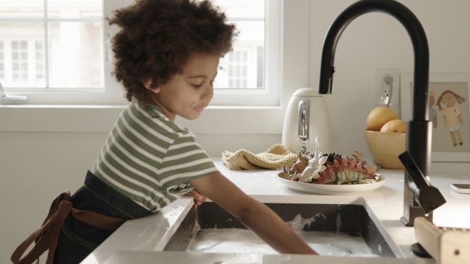 蹒跚学步的孩子在厨房水槽里玩水