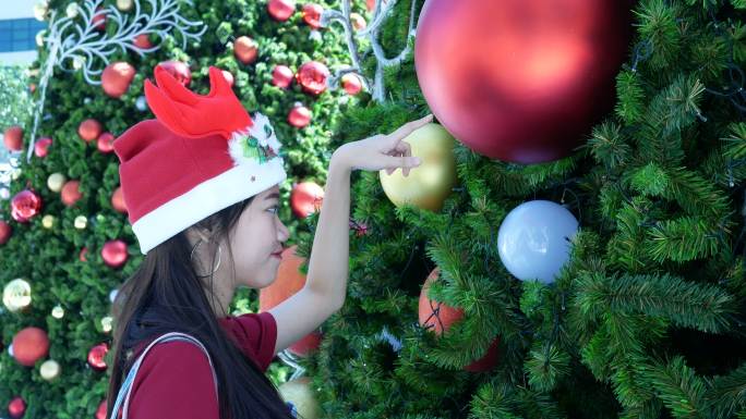 年轻女子在圣诞树上玩圣诞装饰品