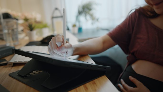 抄写员孕妇在家中使用数字平板电脑。远程工作、怀孕、自由职业