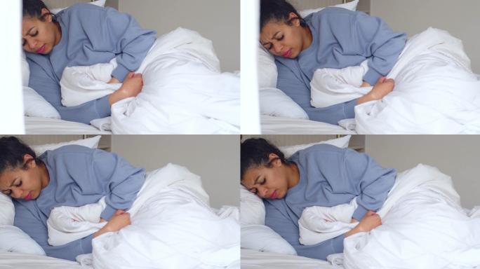 一名年轻女子在家躺在床上时胃痛的4k视频片段