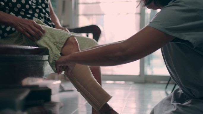 亚洲妇女帮助祖母佩戴护膝设备