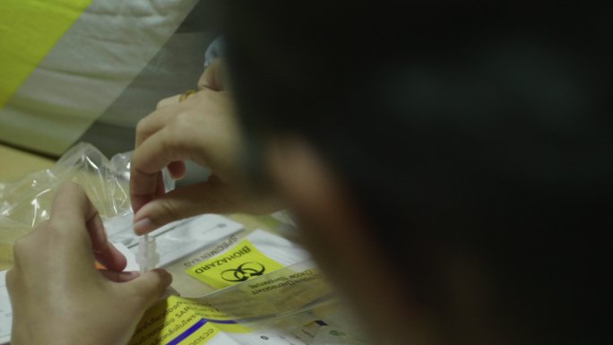 亚洲女性用棉签保存样本以检测新冠肺炎。