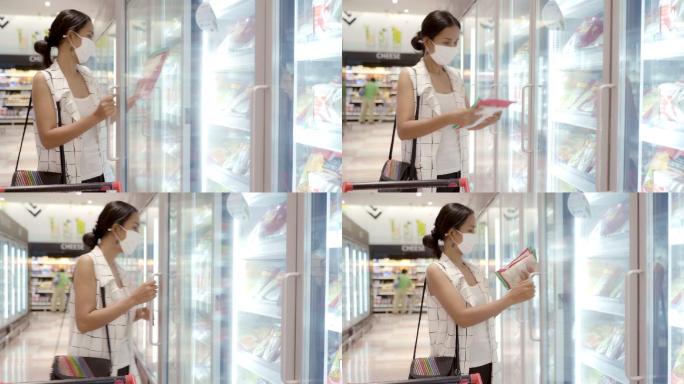 年轻的亚洲女性在超市的深冰箱里挑选产品，并戴上防尘和防病毒的口罩，以保持健康。