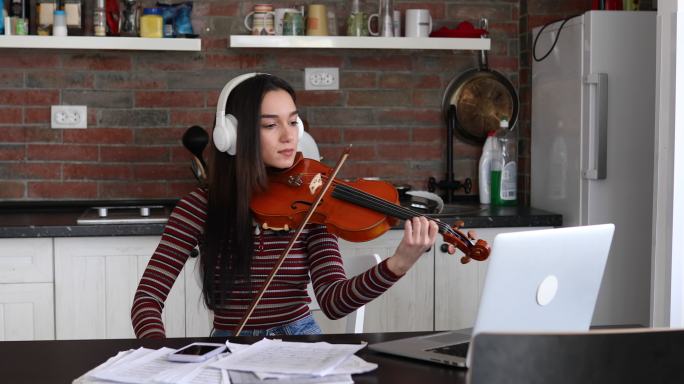重点音乐学校的女生在在线小提琴课上练习拉小提琴。