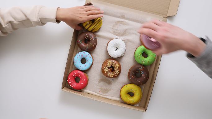 盒子里五颜六色甜甜圈的俯视图。与朋友一起吃外卖的概念