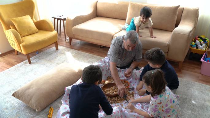 祖父和孙子孙女在家里把核桃和杏仁放在地上