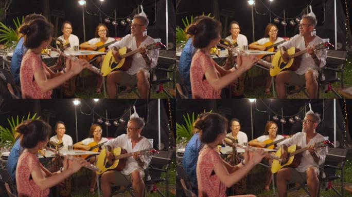 亚洲华人家庭和朋友喜欢在晚上玩乐器，在花园聚会，露营帐篷