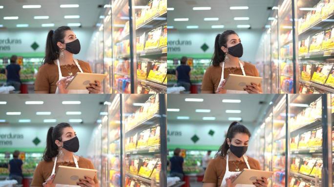 戴口罩的年轻女子使用数码平板电脑控制超市库存