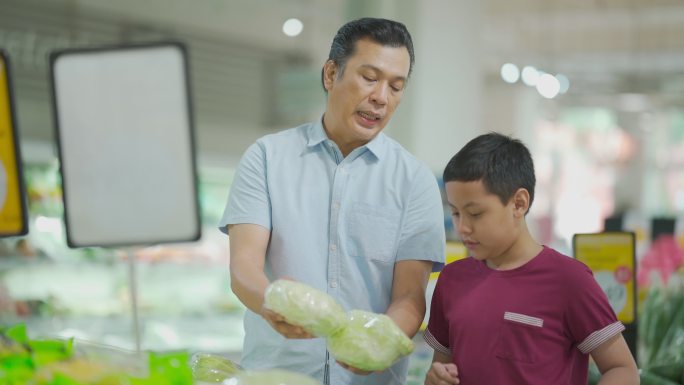 马来中年父子周末携带可重复使用的购物袋在超市购物