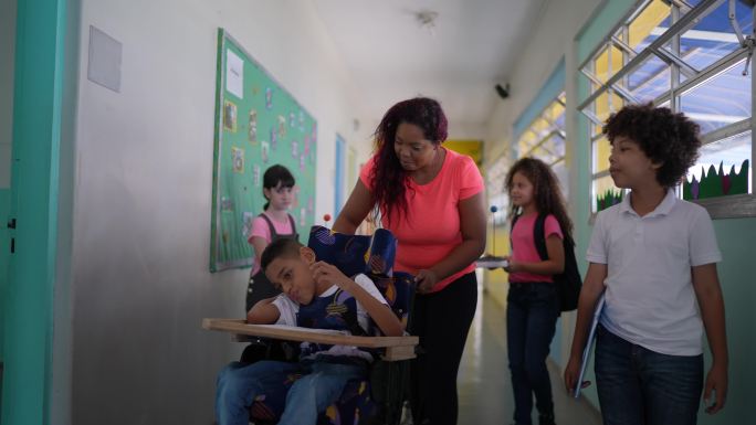 老师和学生在学校走廊里行走——包括一个残疾男孩
