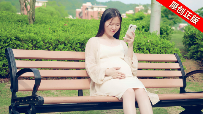 孕妇在公园散步玩手机