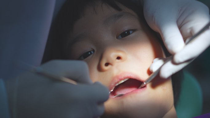 牙医医生的手正在牙科诊所为一名6岁亚洲小孩的牙齿进行治疗