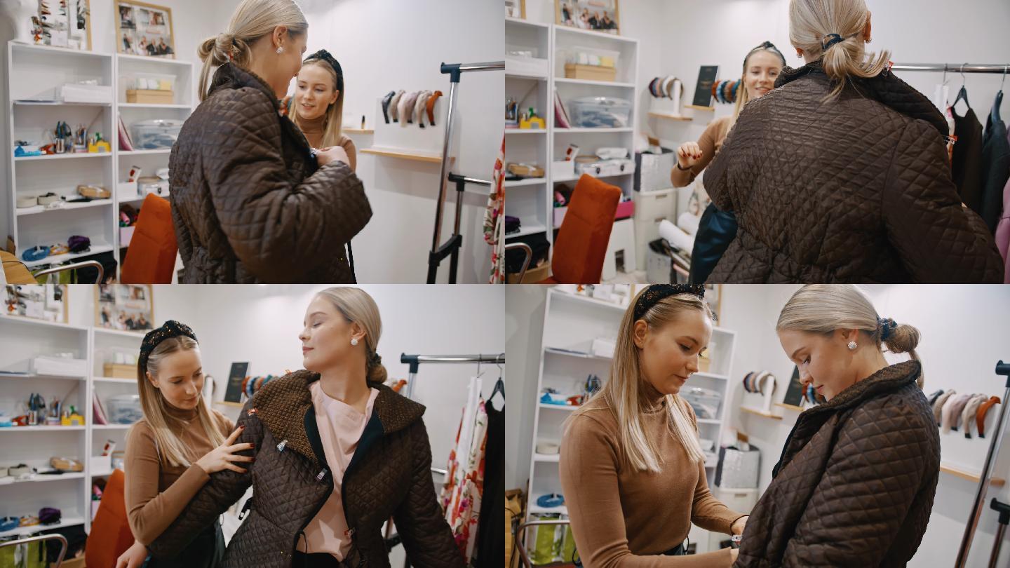 斯洛·莫（SLO MO）年轻的女时装设计师帮助她的顾客穿上她设计的夹克