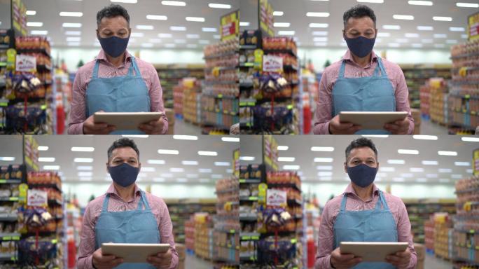 企业主或超市员工手持数字平板电脑使用面罩的肖像