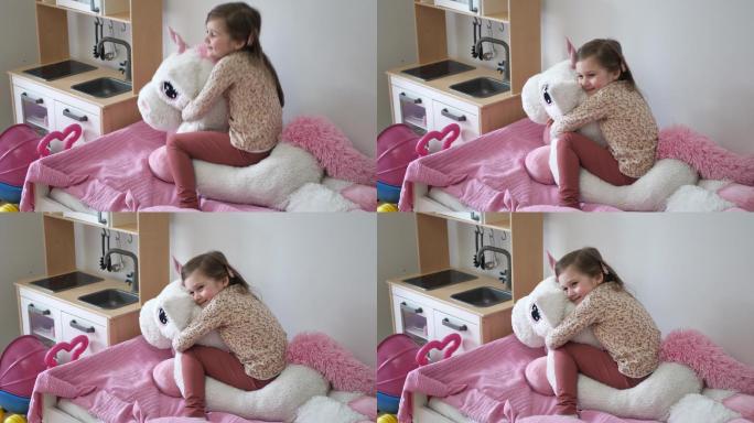 五岁女孩在家玩得很开心，睡前拥抱毛茸茸的独角兽