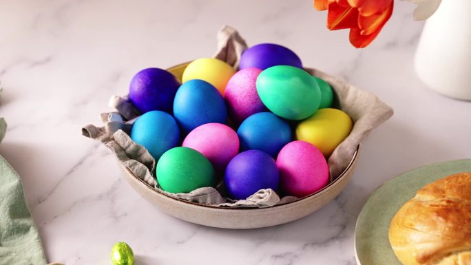 一位女士在桌子上方的碗中摆放五彩复活节彩蛋