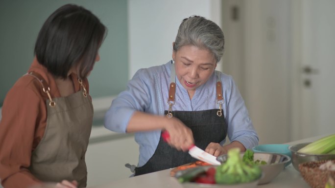 中国亚裔美女和母亲在厨房柜台为家人做饭