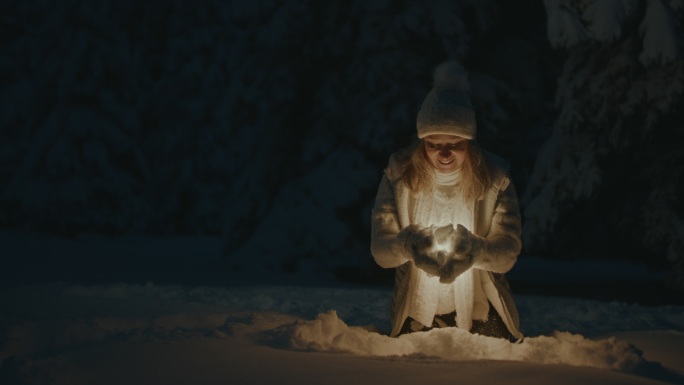 在雪中挖掘并捡起发光物体的女人