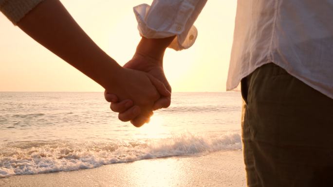情侣们手牵手在海滩上。