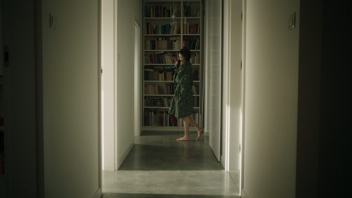 一位年轻女子在家里无聊地用耳机和麦克风在走廊里唱歌