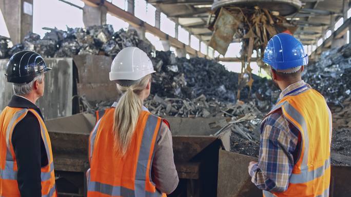 CS运营经理、主管和安全协调员在废料磁铁旁的回收设施谈话