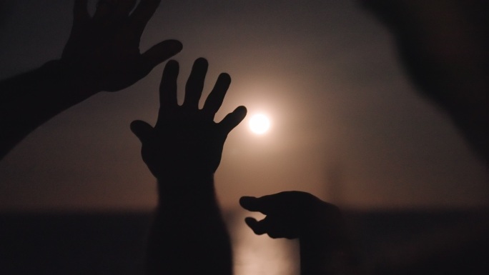 手在满月的映衬下翩翩起舞。海景