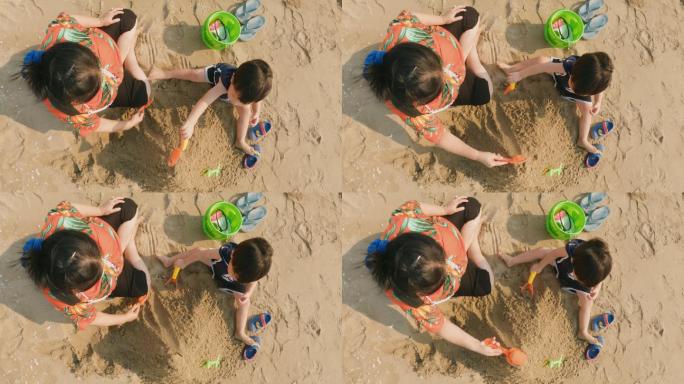 亚洲祖母和孙子在沙滩上玩沙子