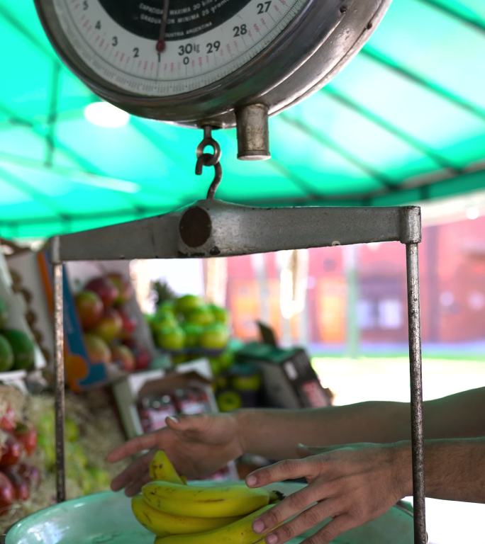 一个面目全非的男子在农贸市场称香蕉重量后抓起香蕉