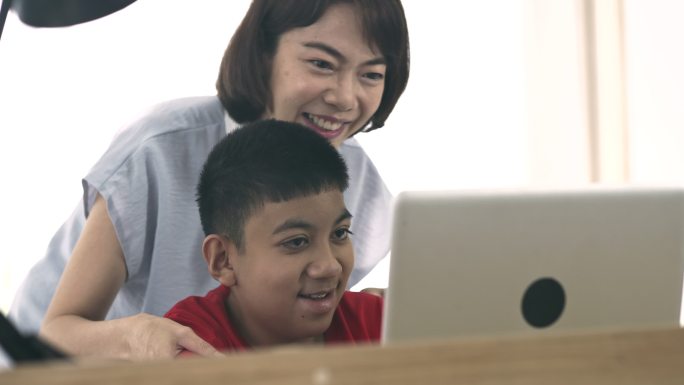 妈妈在家教残疾男孩使用笔记本电脑