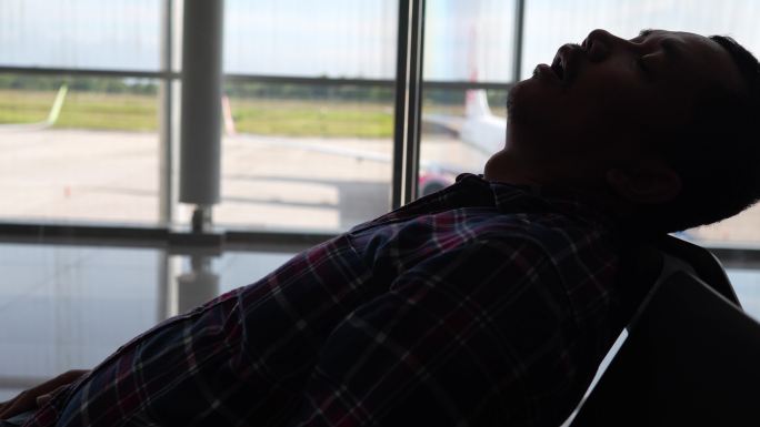 旅行商人在机场内的长椅上休息