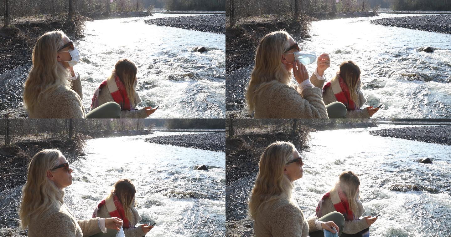 日出时分，成熟的女人和女儿在河岸上放松
