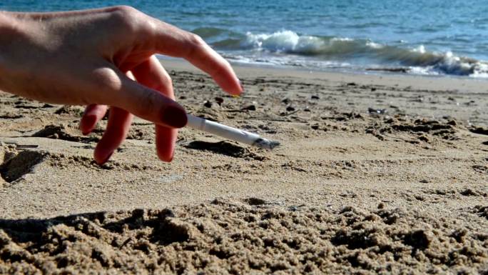 海滩上的香烟抖烟灰弹烟灰海边女人的手抽烟