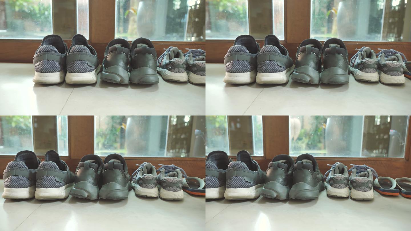 场景中父亲的鞋子和母亲的鞋子紧挨着儿子的鞋子，在家门口附近，家庭物品的概念