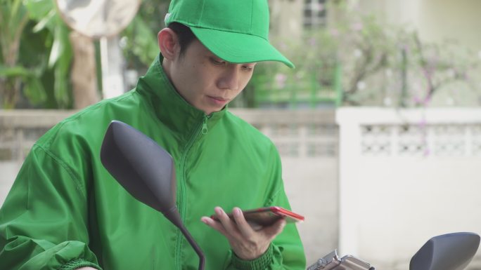 送货的年轻人正在使用智能手机联系客户。