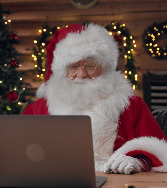 一位聪明的圣诞老人在笔记本电脑上的视频聊天中愉快地解释着一些事情